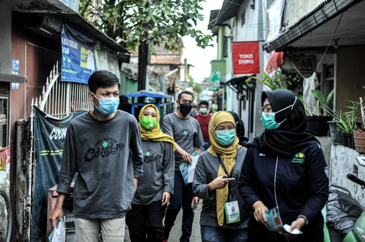 Community health workers walk together, carrying health promotion flyers in the neighborhood alley.